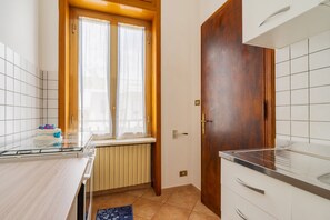 Une cuisine avec une fenêtre, une porte en bois et un mur recouvert de carreaux.
