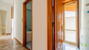 A hallway with wooden doors, a tiled floor, and a view of a bathroom. - Apartment Casa LILLI 11 posti Near the Sea with Sea View, A/C & Balcony (santa maria al bagno)