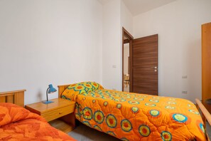 A bedroom with a bed, a nightstand, a desk, and a wardrobe.