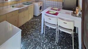 Une cuisine compacte équipée d’un lave-linge, d’un évier et d’un coin repas avec une table et des chaises.