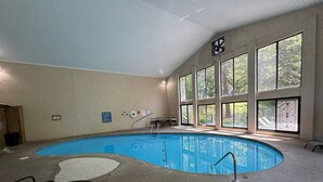 An indoor swimming pool with a view of trees through large windows, a pool ladder, and a table with chairs. - 1 Mile to Dollywood and Pigeon Forge Strip! (Pigeon Forge)