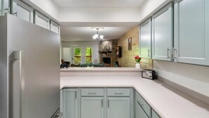 A kitchen with light-colored cabinets, a stone fireplace, and a view into a dining area. - 1 Mile to Dollywood and Pigeon Forge Strip! (Pigeon Forge)