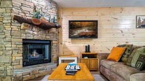 A cozy living room with a stone fireplace, a flat-screen TV, a wooden coffee table, and a comfortable sofa. - 1 Mile to Dollywood and Pigeon Forge Strip! (Pigeon Forge)