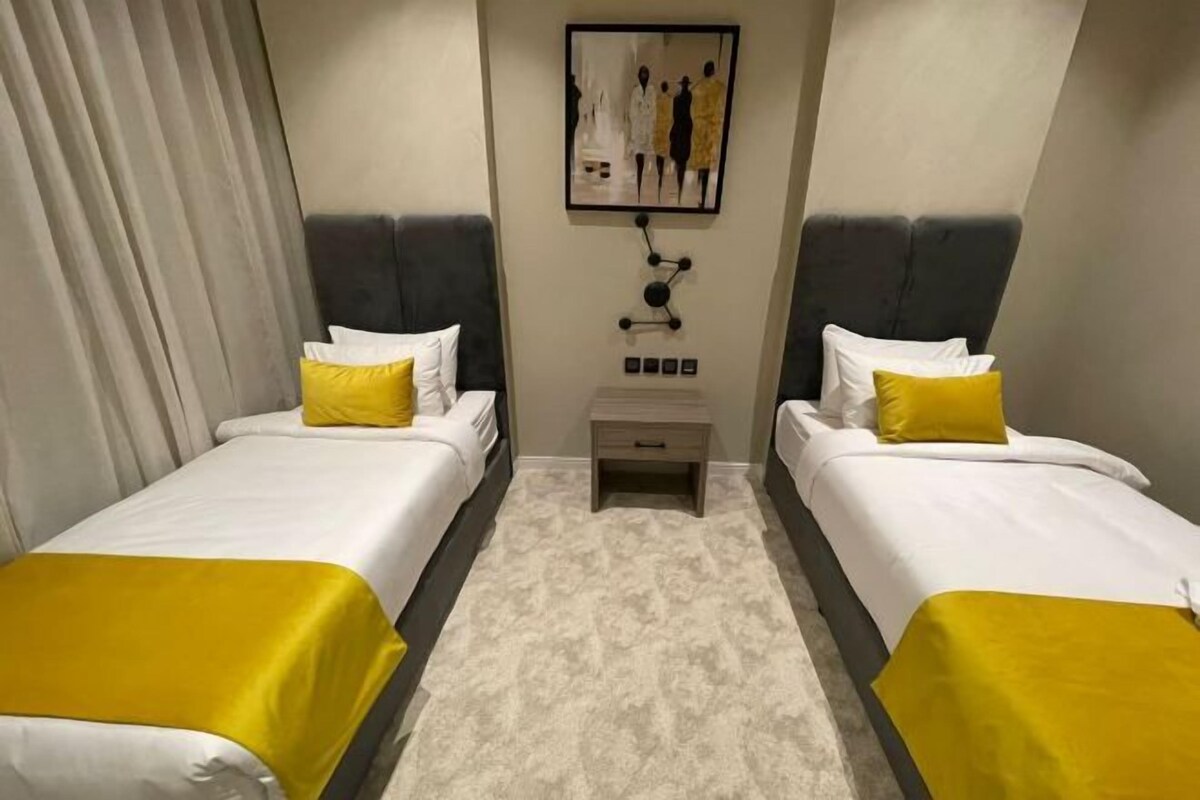 Habitación de hotel con dos camas, una mesita de noche y un cuadro en la pared.