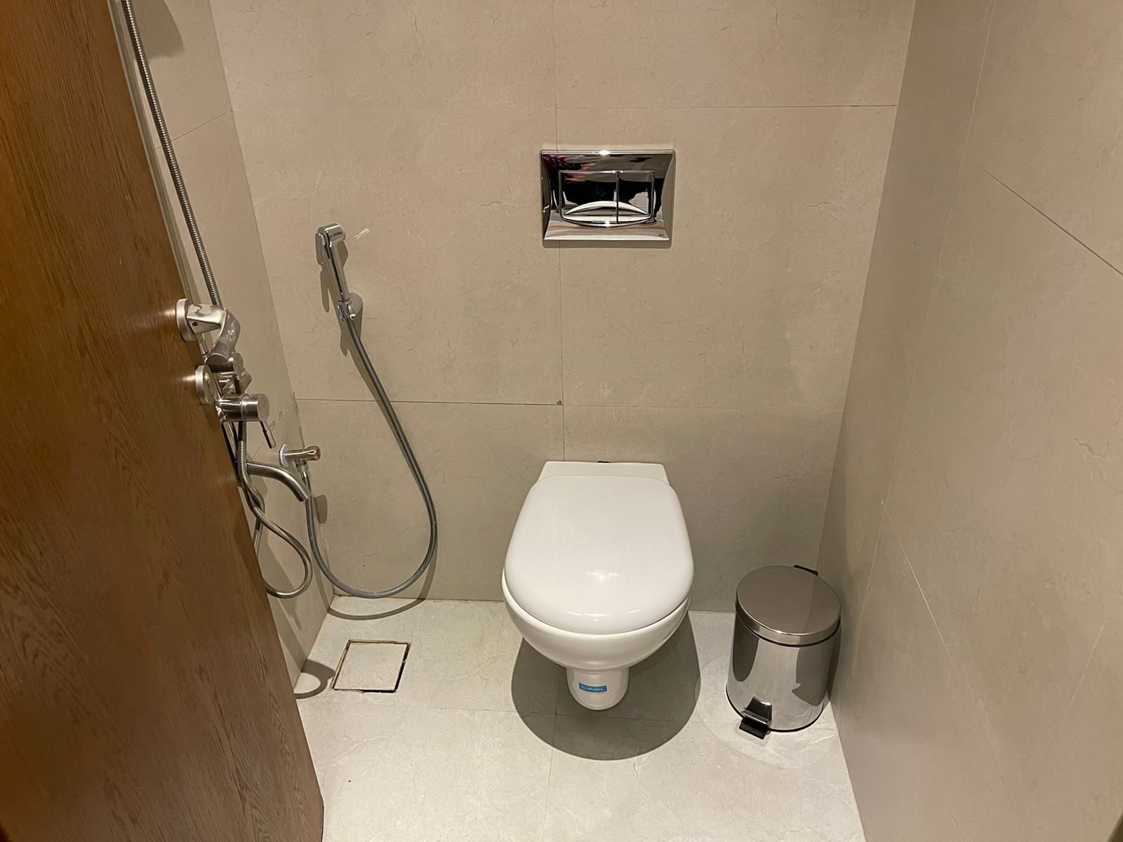 Ein kleines, modernes Badezimmer mit Toilette, Dusche und Mülleimer.