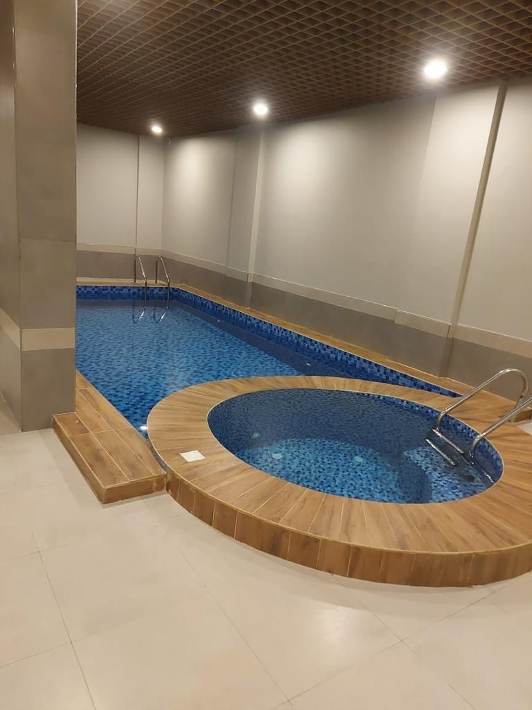 A swimming pool with a wooden deck and a hot tub.