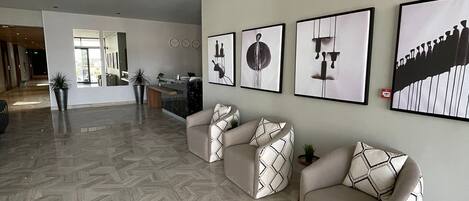 A spacious living area with a herringbone floor pattern, a sofa set, and a wall with framed artwork.