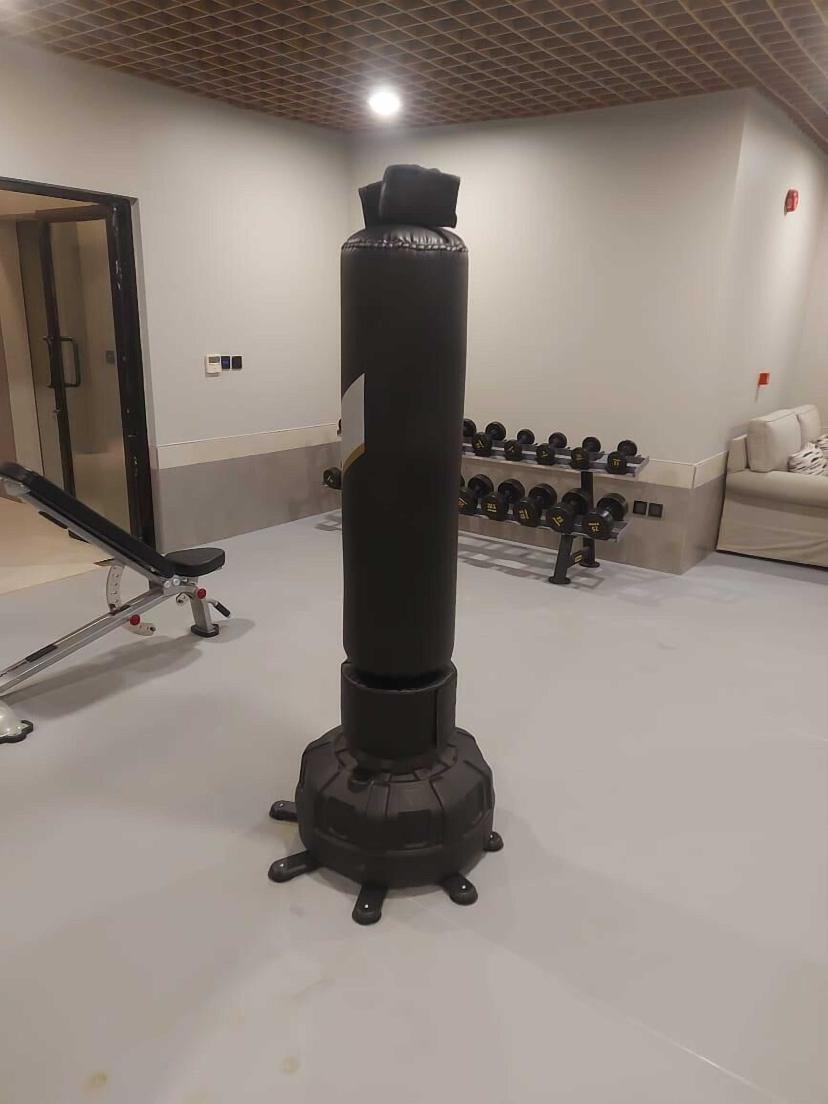 A gym with a punching bag, dumbbells, and a bench.