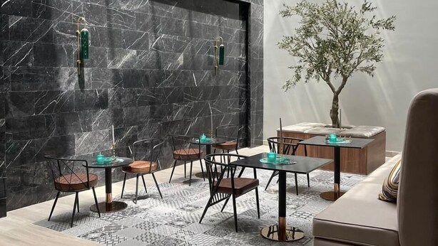 A modern interior with a dining area, a sofa, and a decorative tree. - VOYAGE RESIDENCE (Riyadh)