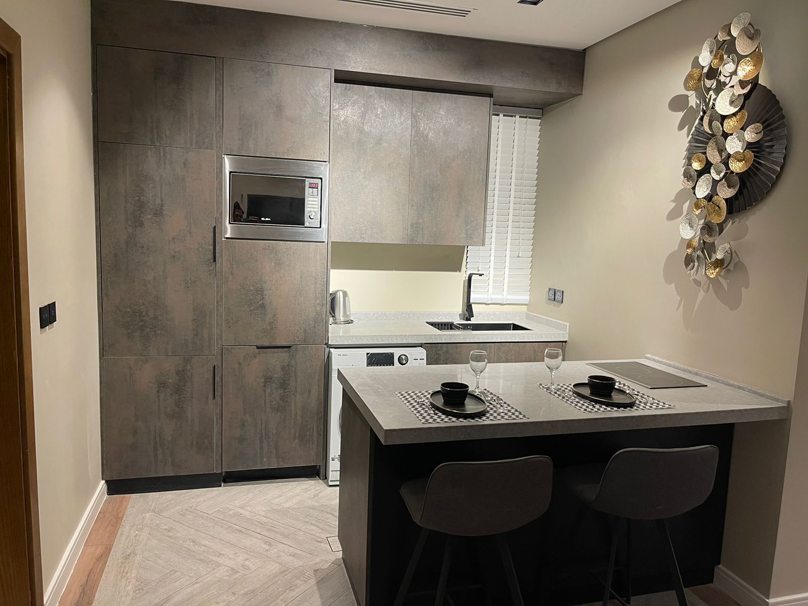 A modern kitchen with a central island, built-in appliances, and a decorative wall piece.