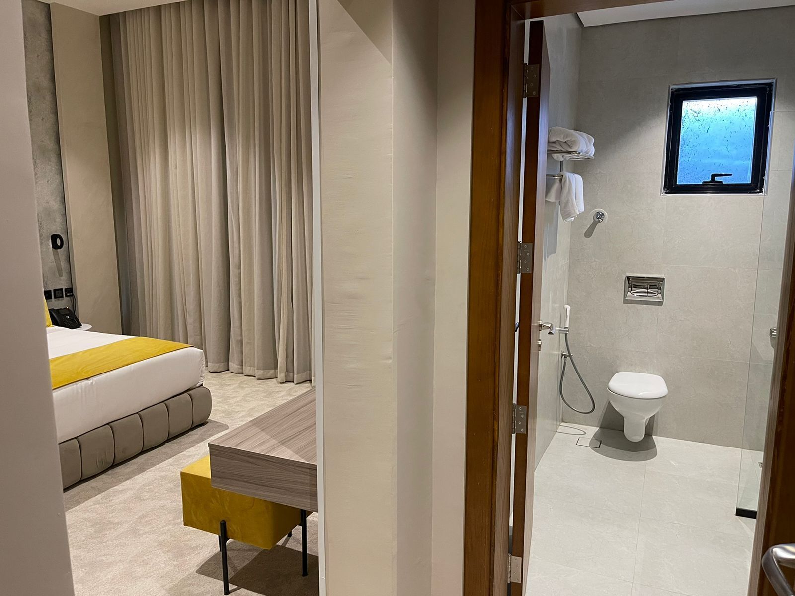 Habitación de hotel con cama, una mesita, zona de ducha y vista al mar por la ventana.