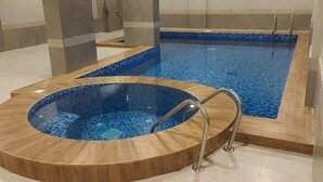 A swimming pool with a wooden deck and a separate hot tub area. - VOYAGE RESIDENCE (Riyadh)