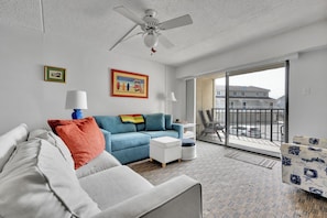 Relax in this inviting living space with a sofa, armchair, and ottoman, plus a balcony with a view.