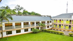 A two-story building with a flat roof, multiple balconies, and a central courtyard with grass and small plants.