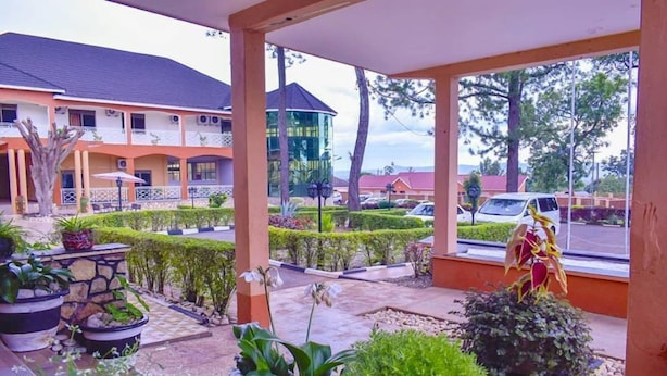 A hotel with a covered outdoor area featuring potted plants and a view of the parking lot.
