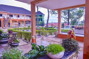 A hotel with a covered outdoor area featuring potted plants and a view of the parking lot. - ROCK CLASSIC HOTEL LIMITED (Tororo)