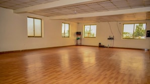 A spacious room with wooden flooring, large windows, and a ceiling with a grid pattern.