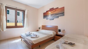A bedroom with a bed, a bedside table, a nightstand, a window with curtains, and a painting on the wall. - Bilo Danilo Few Minutes From Sea (Loiri Porto San Paolo)