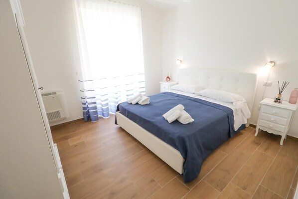 A bedroom with a bed, bedside tables, a nightstand, a window with curtains, and a radiator. - Double bed and sofa bed (Laureana Cilento)