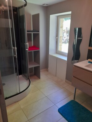Ein Badezimmer mit Dusche, Fenster und Waschbecken.
