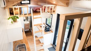 Cocina compacta con una escalera de madera, un lavamanos y un pequeño comedor.