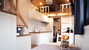 Una cocina compacta con armarios blancos, encimera de madera y una lámpara colgante.