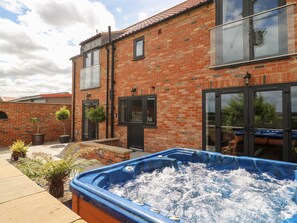 A brick building with large windows and a hot tub in the foreground. - The Old Doghouse (York)