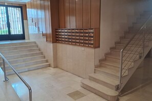 A staircase with metal railings, a wooden wall with mailboxes, and a tiled floor. - Desconectaengalicia Cesteiros, swimming pool, 100m Beach (Sanxenxo)