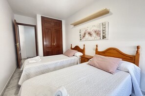 Ein Hotelzimmer mit zwei Betten, einem Holzschrank, einem Bild an der Wand und einem Regal über dem Bett.