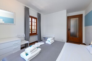 A hotel room with a bed, a desk, a chair, a wardrobe, and a window with curtains. - Appartamento del Marinaio (Malcesine)