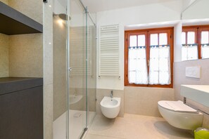 A modern bathroom with a glass shower enclosure, a bidet, and a toilet. - Appartamento del Marinaio (Malcesine)