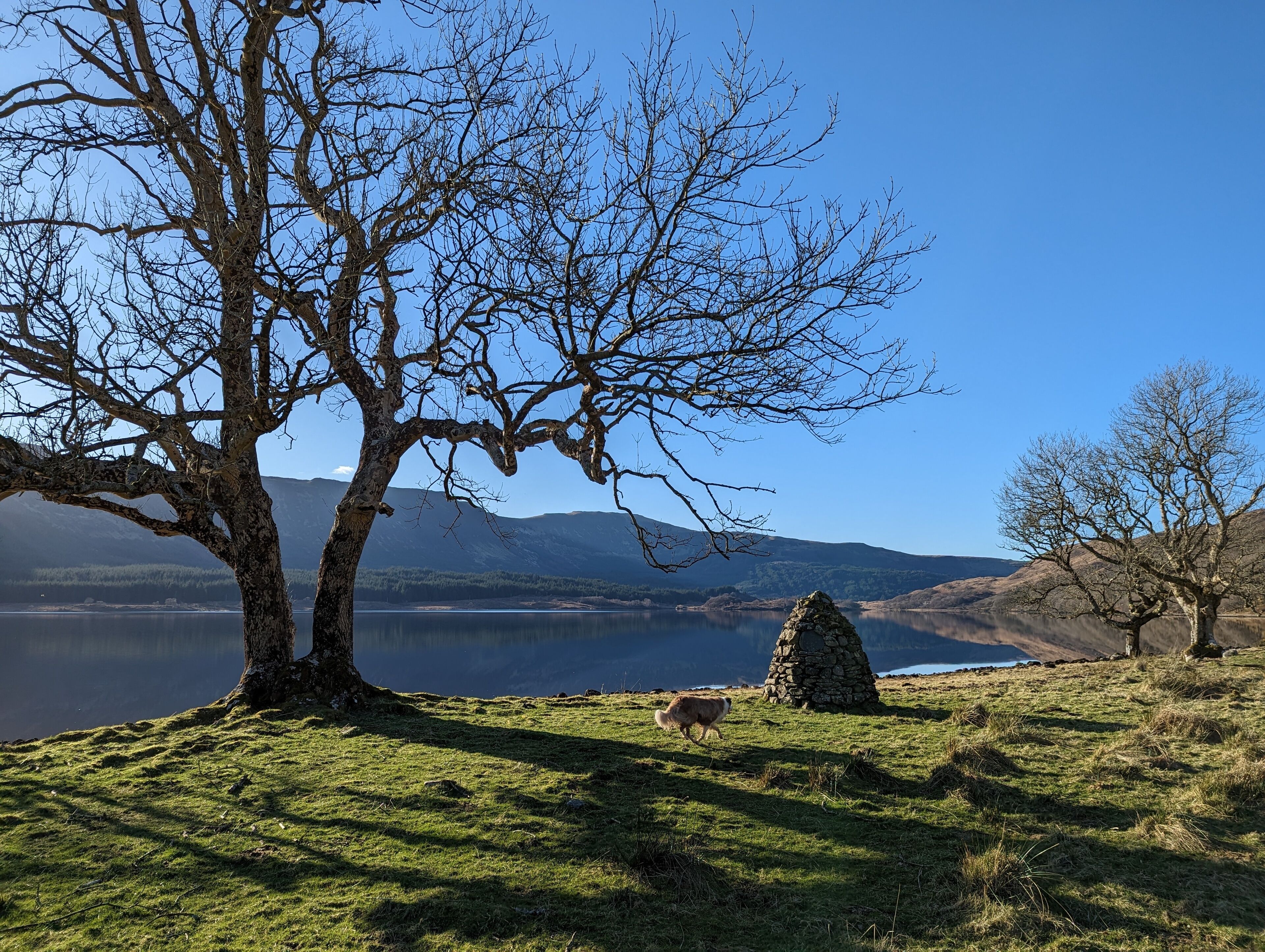A serene landscape with a lake, mountains, and a stone structure.