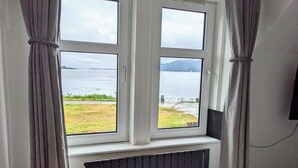 Una habitación con ventana que da a un lago y un área verde.