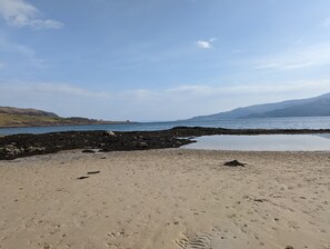 A beach with footprints, a rocky area, and a calm sea under a clear sky. - Lochaline Hotel (Oban)