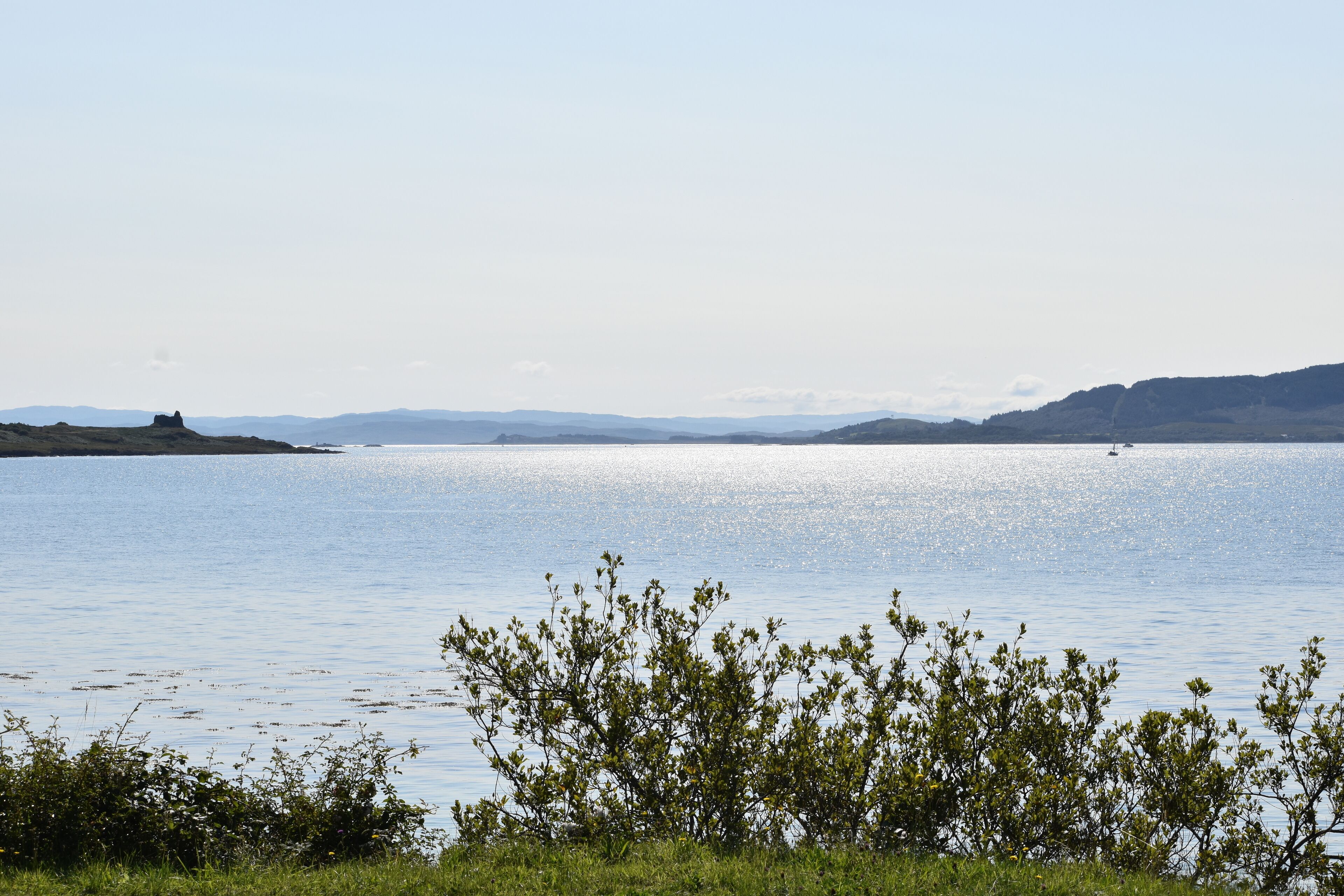 Un lago tranquilo con colinas a lo lejos y un cielo despejado.