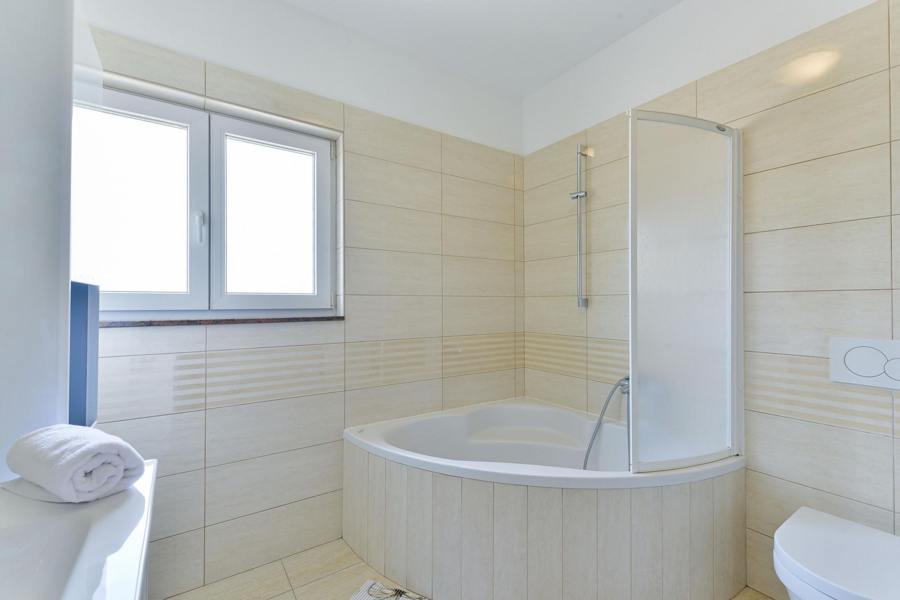 Un baño moderno con bañera, inodoro y ventana.