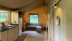 A cozy kitchen with wooden cabinets, a sink, and a dining area with a bench. - Glamping TENTE LODGE SAFARI DE LUXE, vue sur le coteau et vignes (Chadenac)