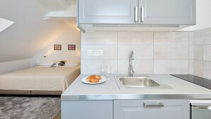 Una cuina compacta amb un sol rentaplat, una petita barra i un llit a la sala adjacent.