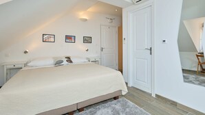 Un dormitori amb un llit gran, una porta blanca i un ventilador de sostre.