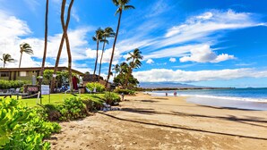 A beach with palm trees, a building with a sign, and the ocean.