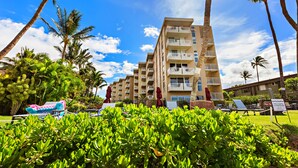 A multi-story hotel with balconies, surrounded by lush greenery and palm trees.