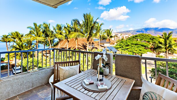 A balcony with a wooden table, chairs, and a bottle of champagne.