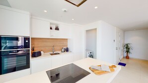 Una cocina moderna con electrodomésticos integrados, salpicadero de madera y una isla central.