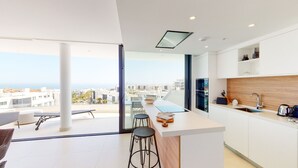 Una cocina moderna con una isla grande, taburetes de bar y vistas a la ciudad.