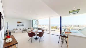 Una sala de estar moderna con comedor, ventanas grandes y vistas a la ciudad.