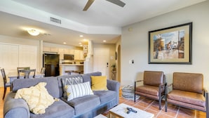 A living room with a gray sofa, two brown chairs, a coffee table, and a painting on the wall.