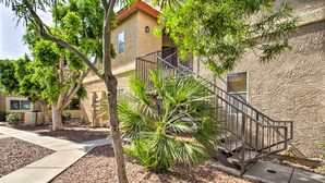 A residential building with a stucco exterior, a metal staircase, and a palm tree in the foreground.