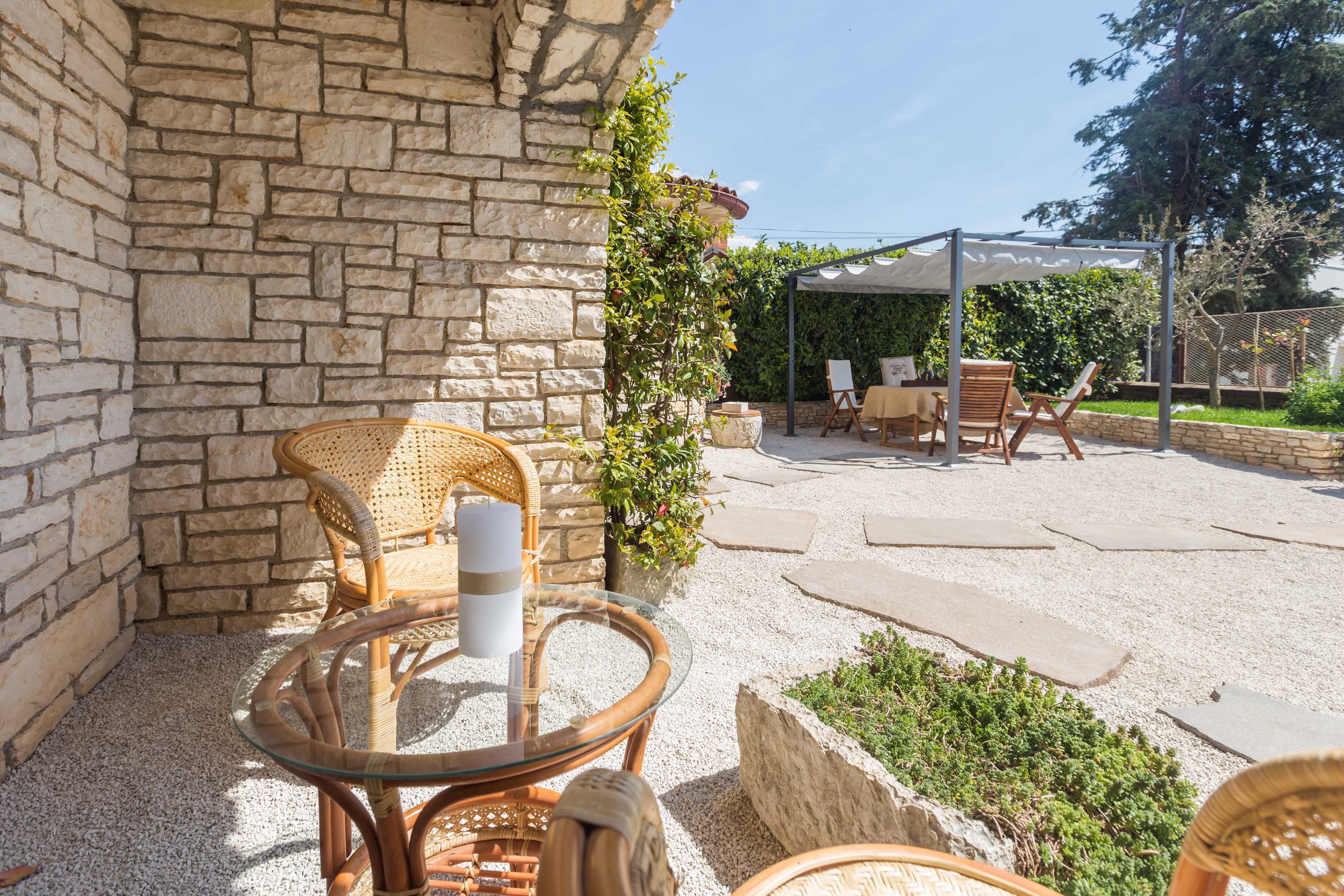 An outdoor patio with stone walls, wicker furniture, and a covered seating area.