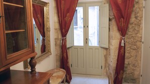 A room with a wooden dresser, a bench, a mirror, and red curtains. - 2 BR apt., gated courtyard, right by ocean & sites (Siracusa)
