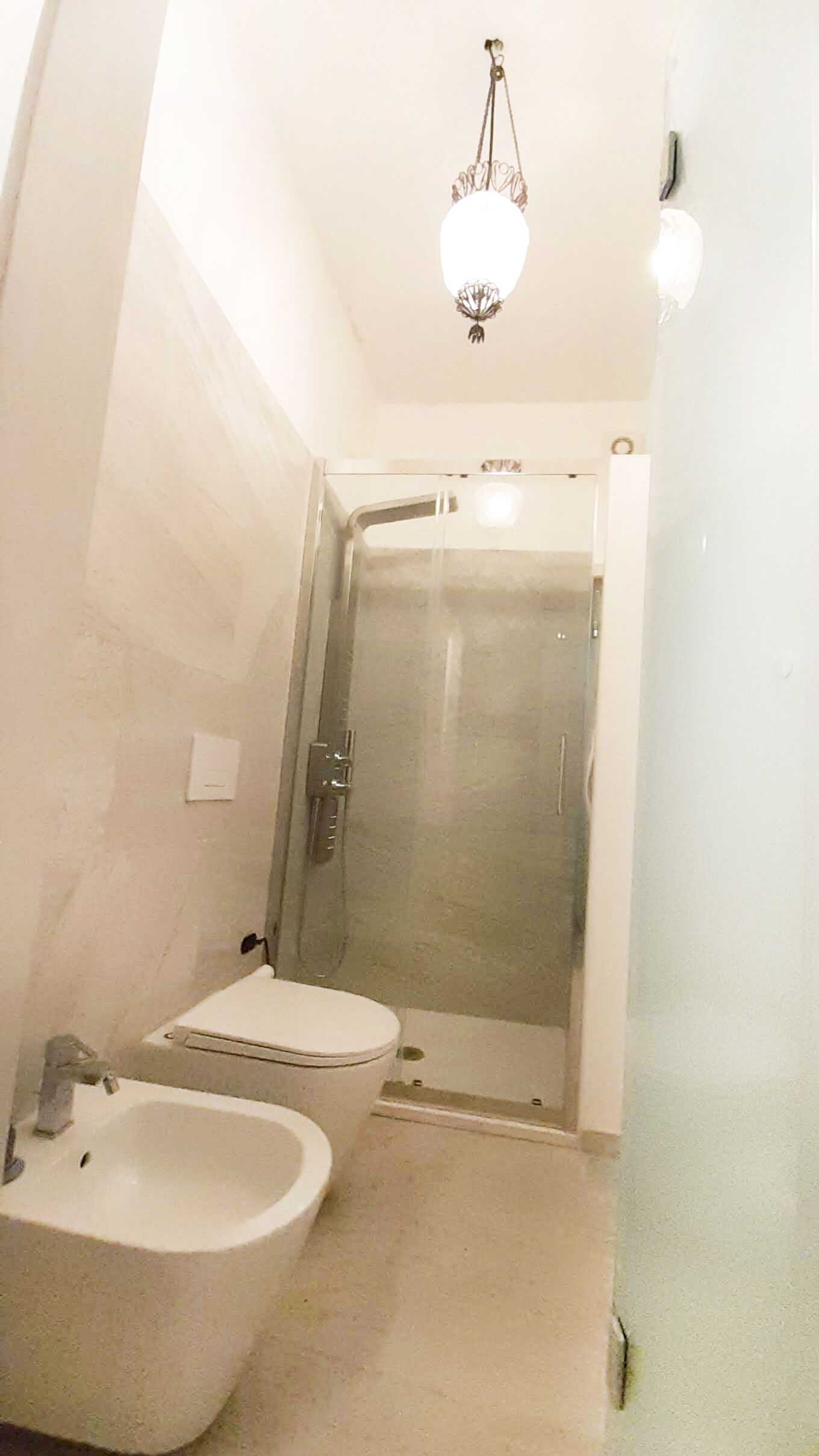 Une salle de bain équipée de toilettes, d’un bidet et d’une douche à parois de verre.